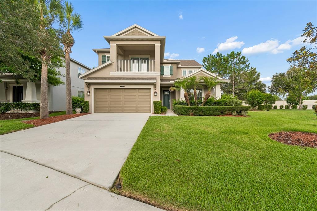 A two-story suburban house with a tan exterior, a two-car garage, and a front balcony — 9323 BELLA VITA CIRCLE, LAND O LAKES, FL