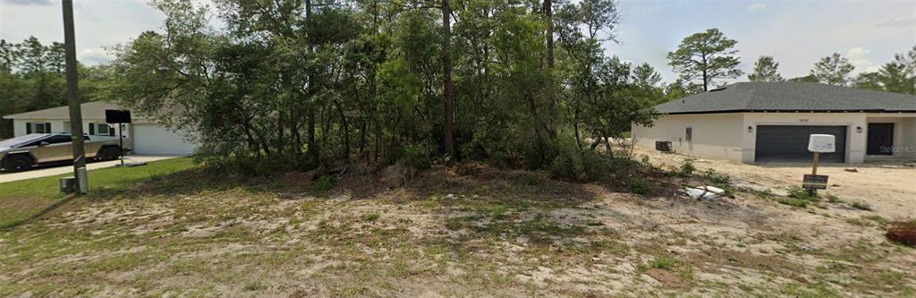 A vacant, wooded residential lot sits between two single-story houses in a suburban neighborhood — TBD SW 69TH CT ROAD, OCALA, FL