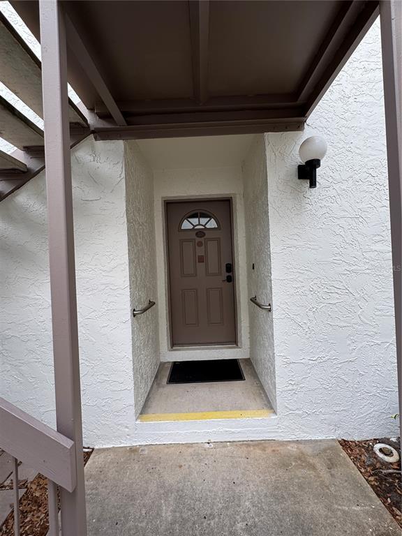An exterior view of a recessed front door with a small porch and stairs — 511 LONGFELLOW COURT UNIT B, SAFETY HARBOR, FL