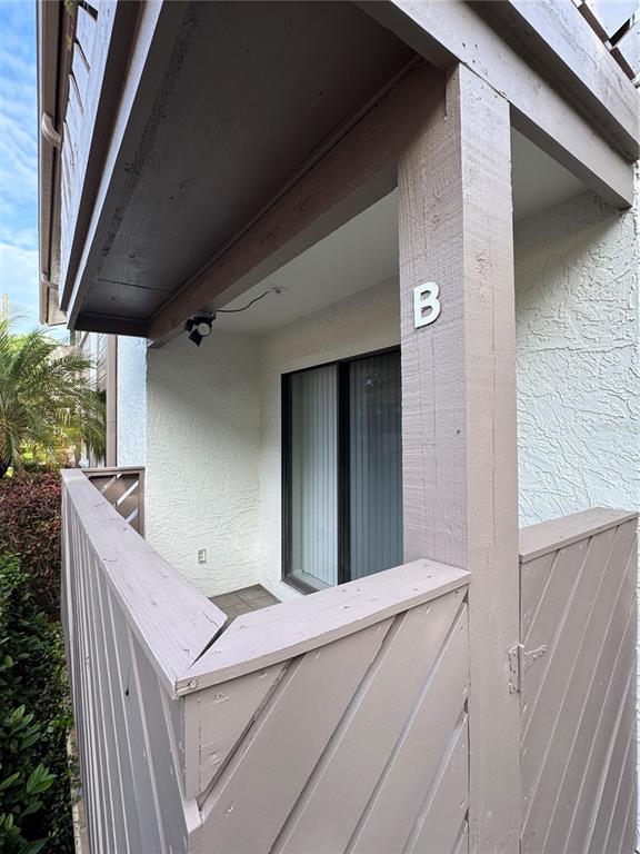 A covered balcony with a wooden railing and a sliding glass door labeled B — 511 LONGFELLOW COURT UNIT B, SAFETY HARBOR, FL