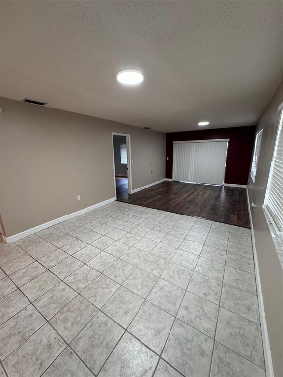 A room with light-colored tile flooring transitions to dark wood flooring near a sliding door — 511 LONGFELLOW COURT UNIT B, SAFETY HARBOR, FL