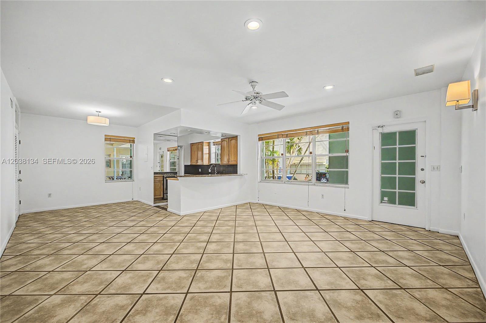 An open-concept living area features tile flooring, a ceiling fan, and a kitchen pass-through window — 1751 Washington Ave # 1F, Miami Beach FL 33139, MIAMI BEACH, FL