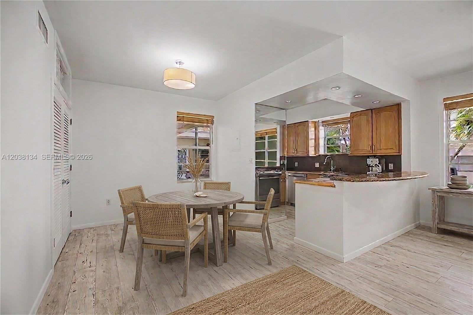A dining area with a round table and chairs sits adjacent to an open kitchen — 1751 Washington Ave # 1F, Miami Beach FL 33139, MIAMI BEACH, FL