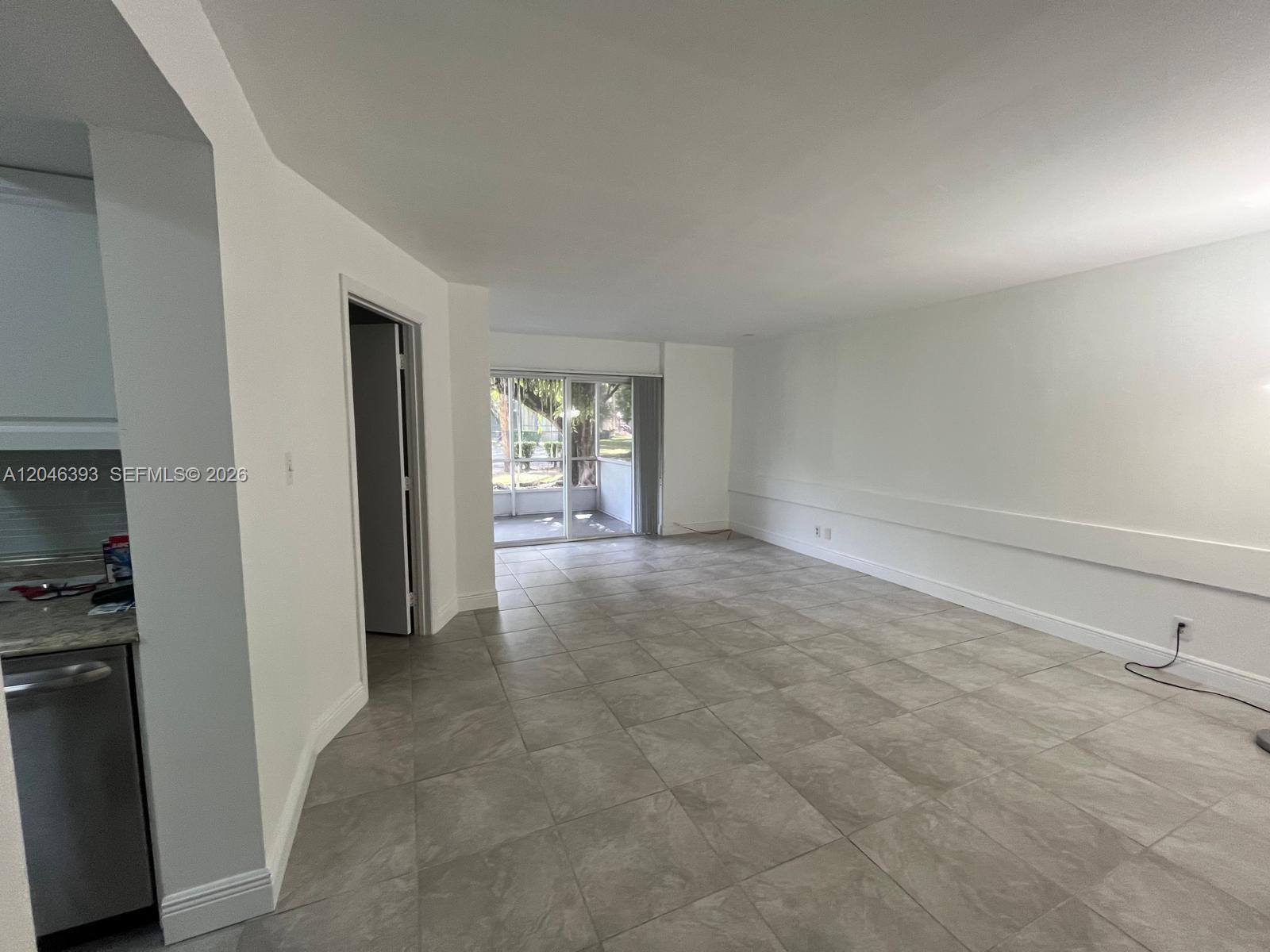 An open-concept living area features light gray tile flooring, white walls, and a sliding glass door — MIAMI, FL