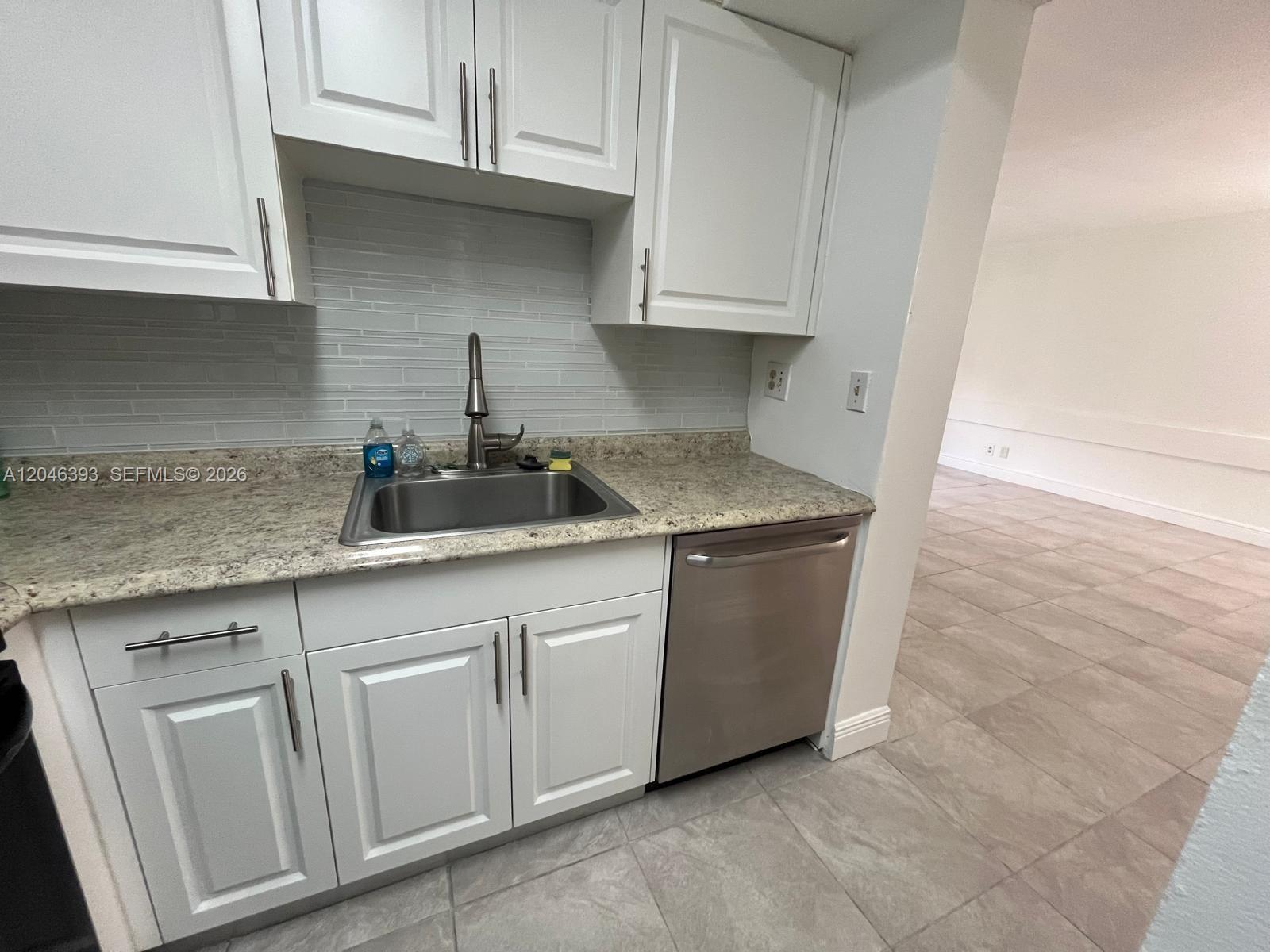 A kitchen features white cabinets, granite countertops, a stainless steel sink, and a dishwasher — MIAMI, FL
