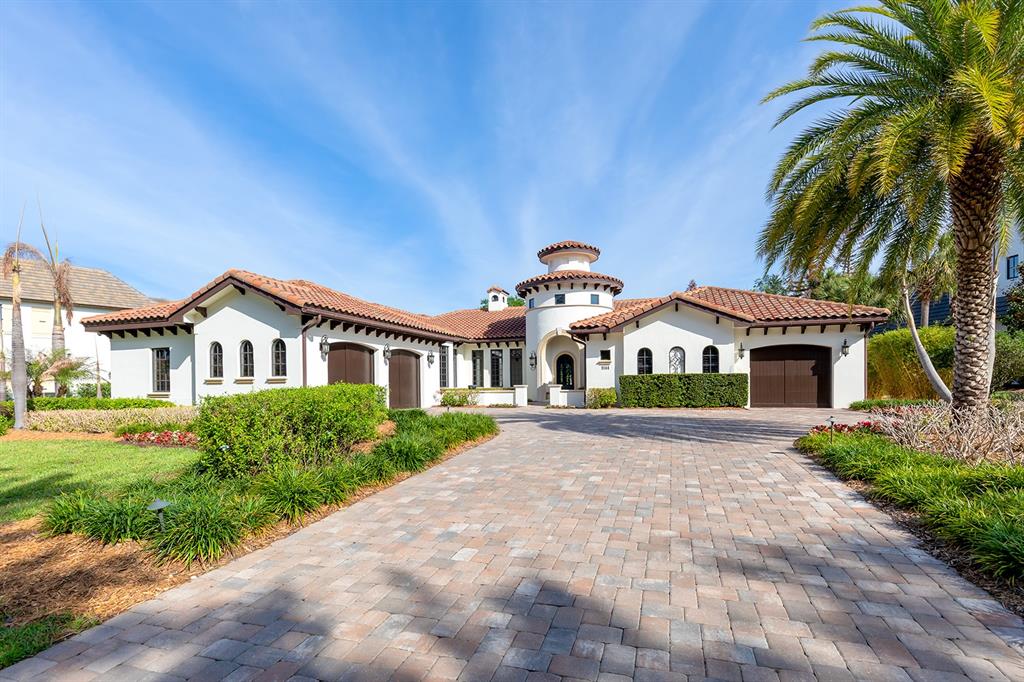 A single-story Mediterranean-style house features a tiled roof, a central tower, and a paved driveway — 9144 ISLEWORTH GARDENS DRIVE, WINDERMERE, FL
