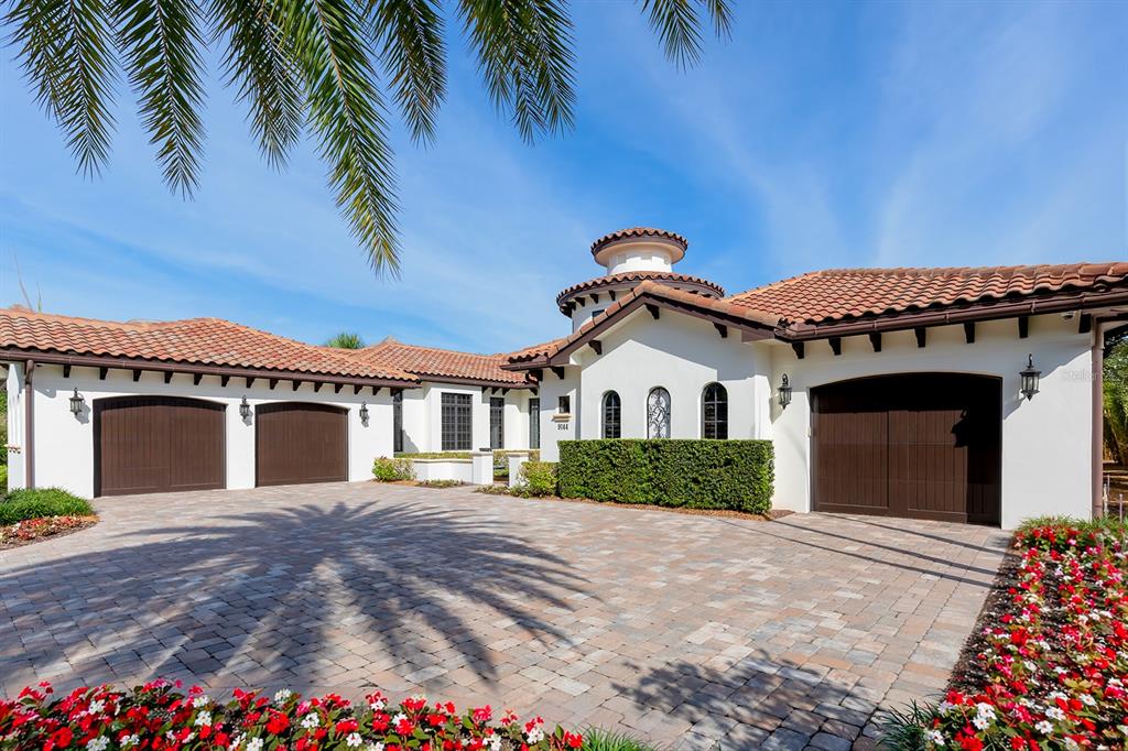 A white stucco house with a tiled roof and three garage bays features a paved driveway — 9144 ISLEWORTH GARDENS DRIVE, WINDERMERE, FL
