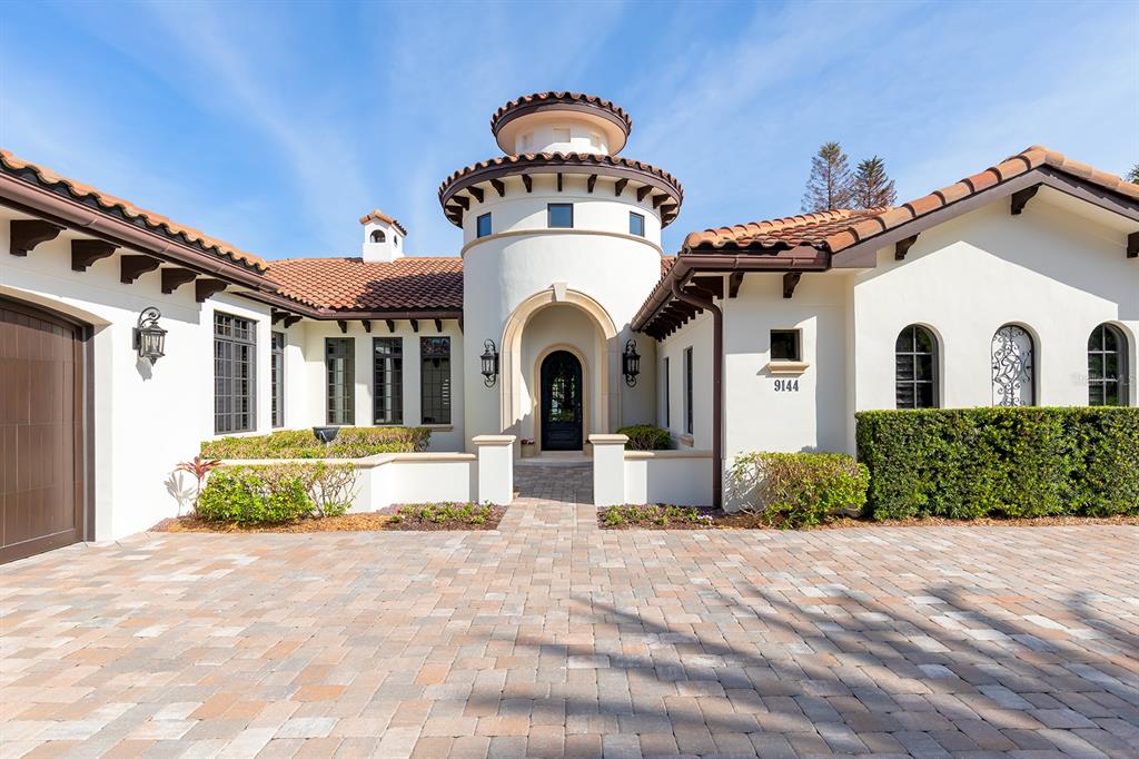 A Mediterranean-style house exterior features a central turret, arched entryway, and a paved driveway — 9144 ISLEWORTH GARDENS DRIVE, WINDERMERE, FL