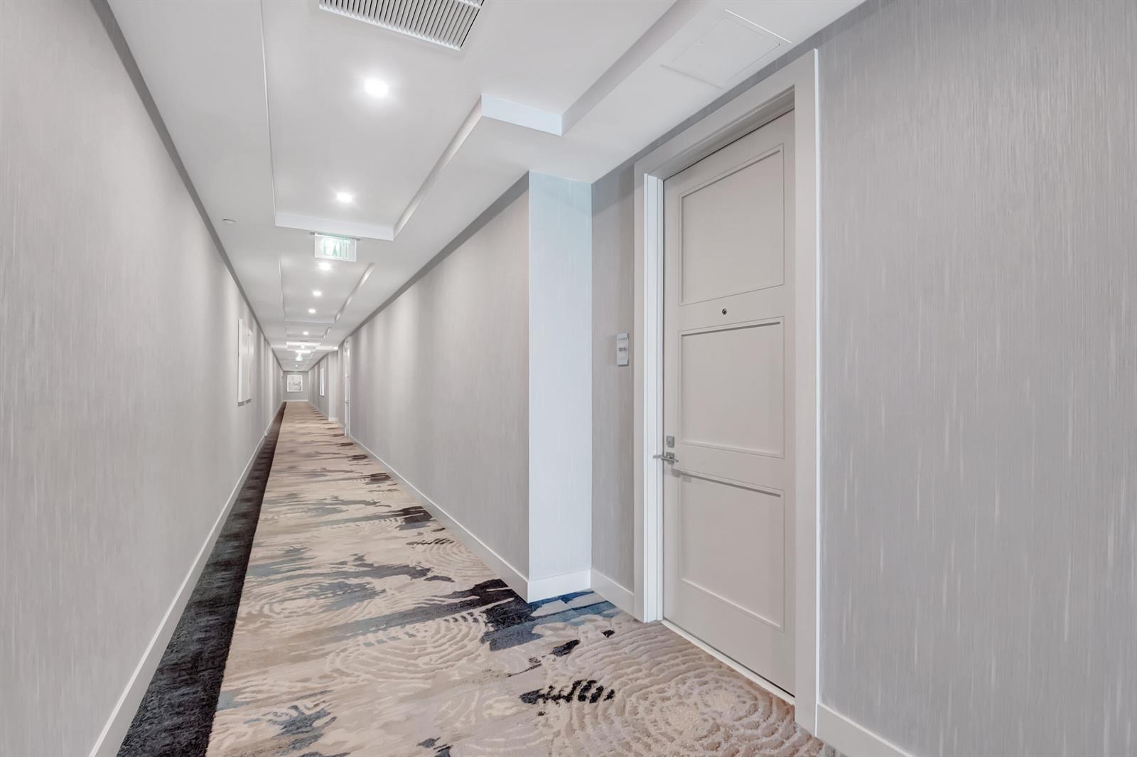 A long hotel hallway features light gray walls, patterned carpeting, and a single closed door — 155 E Boca Raton Road # 1014, Boca Raton FL 33432, BOCA RATON, FL