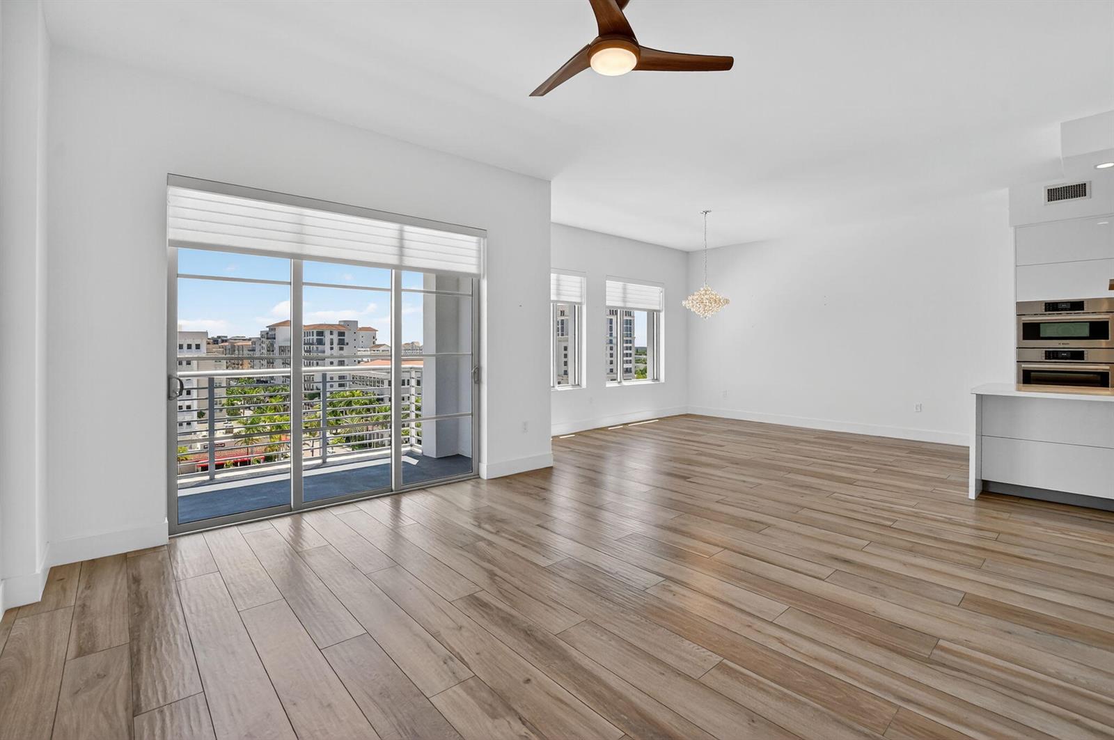 An open-concept living area features light wood-look flooring, a ceiling fan, and a balcony view — 155 E Boca Raton Road # 1014, Boca Raton FL 33432, BOCA RATON, FL