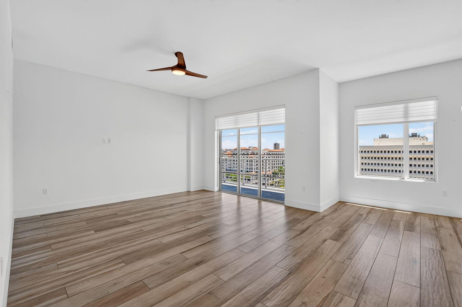 An empty room features light wood-look flooring, white walls, a ceiling fan, and balcony access — 155 E Boca Raton Road # 1014, Boca Raton FL 33432, BOCA RATON, FL