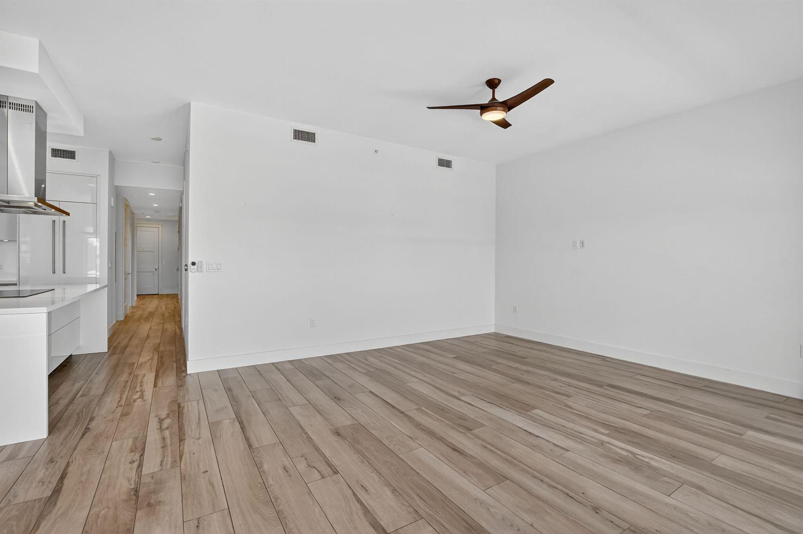 An empty living room with white walls, light wood-look flooring, and a ceiling fan — 155 E Boca Raton Road # 1014, Boca Raton FL 33432, BOCA RATON, FL