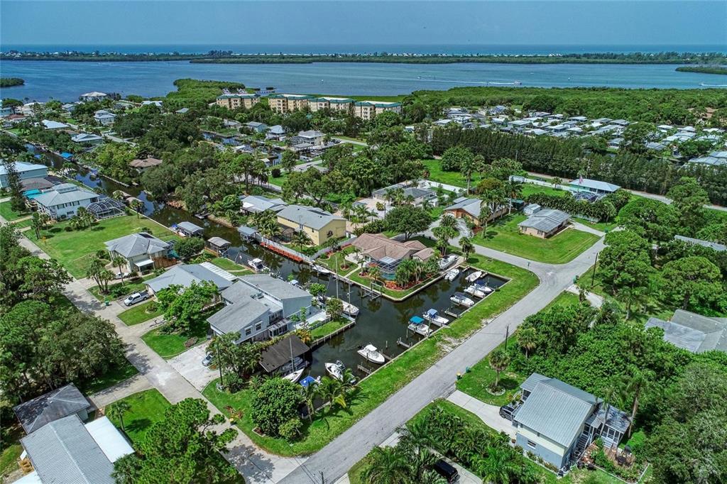 An aerial view shows waterfront houses along a canal leading to a large bay — 9130 PINE COVE DRIVE UNIT B82, ENGLEWOOD, FL
