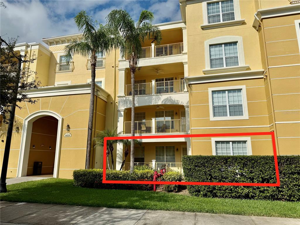 The exterior of a multi-story apartment building features a ground-floor unit with a patio — 5025 SHOREWAY LOOP UNIT 105, ORLANDO, FL