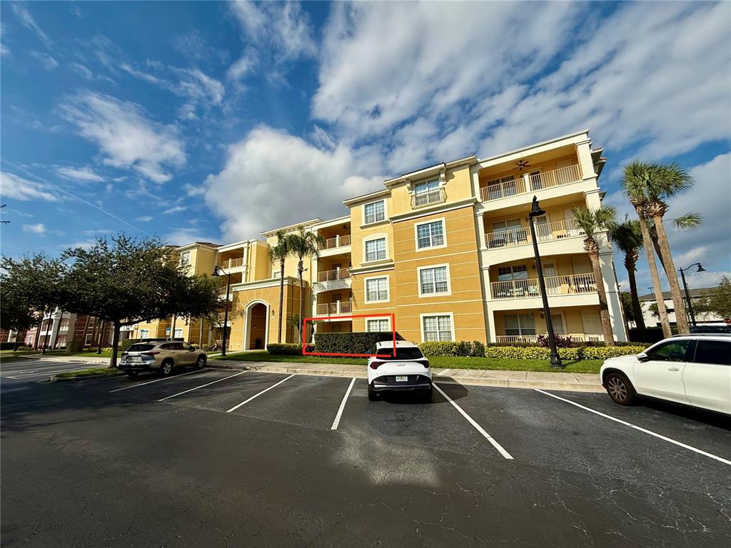 A multi-story yellow apartment building with a ground-floor patio enclosed by a hedge — 5025 SHOREWAY LOOP UNIT 105, ORLANDO, FL