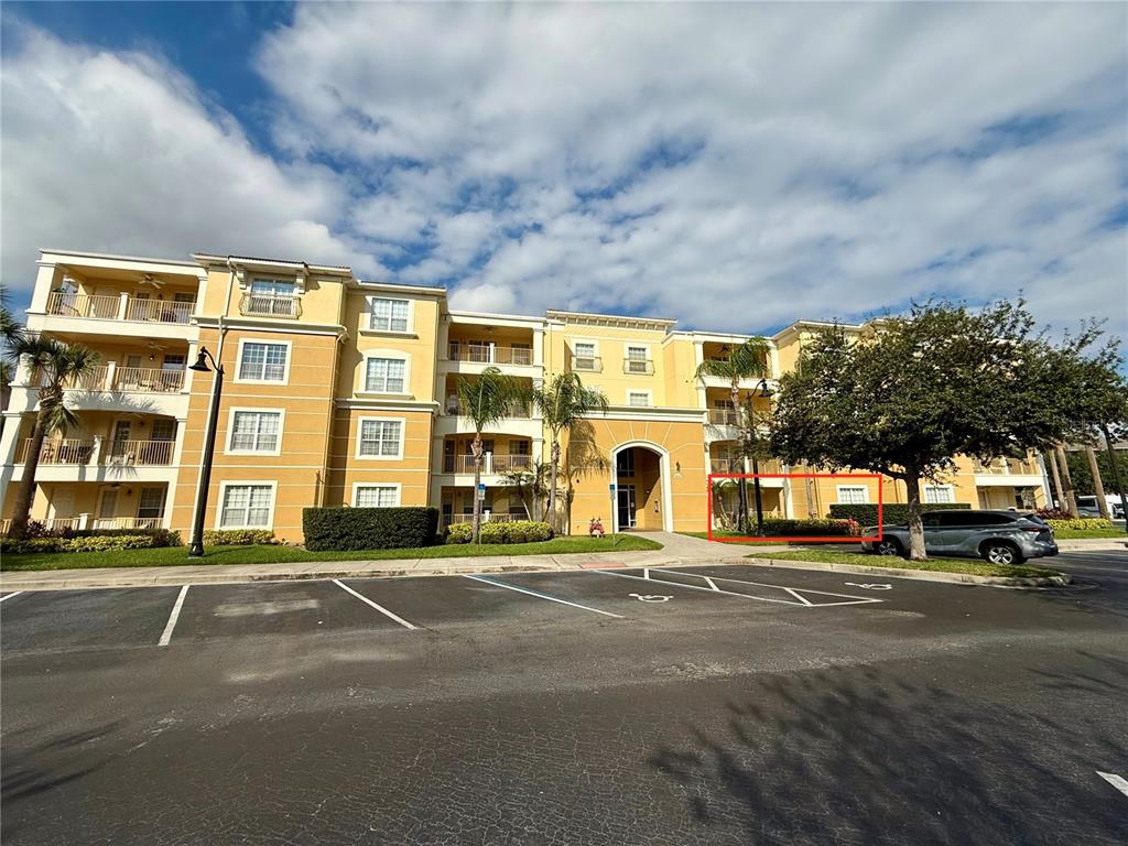 A multi-story yellow apartment building with a parking lot in the foreground — 5025 SHOREWAY LOOP UNIT 105, ORLANDO, FL