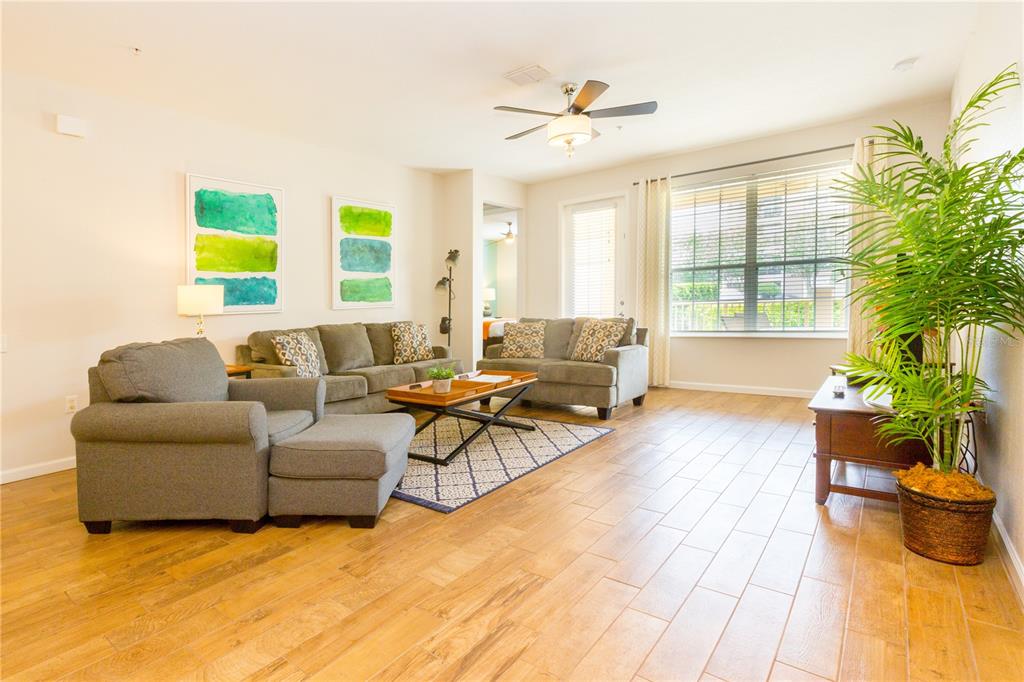 A living room features gray sofas, a wooden coffee table, a ceiling fan, and tile flooring — 5025 SHOREWAY LOOP UNIT 105, ORLANDO, FL