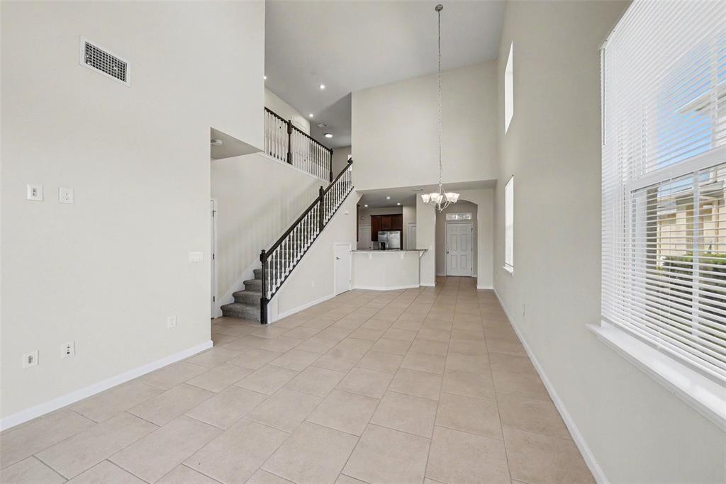 An open-concept living area features high ceilings, tile flooring, a staircase, and a kitchen view — 10711 VERAWOOD DRIVE, RIVERVIEW, FL