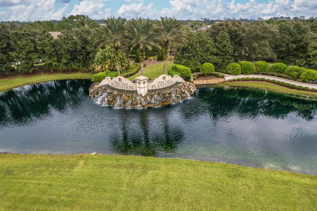 An aerial view shows a waterfall feature with signage for Palm Coast Plantation in a pond — 78 N LAKEWALK DRIVE, PALM COAST, FL