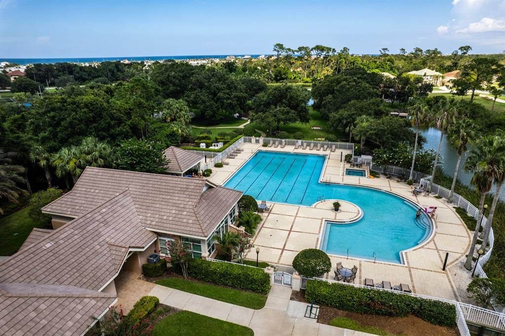 An aerial view of a community swimming pool and clubhouse surrounded by trees and landscaping — 78 N LAKEWALK DRIVE, PALM COAST, FL