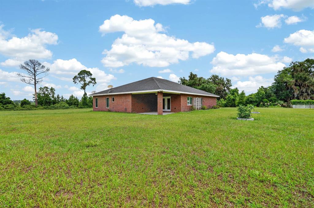 A brick house with a hip roof sits in the middle of a large field — 115 TANGELO TERRACE, CRESCENT CITY, FL