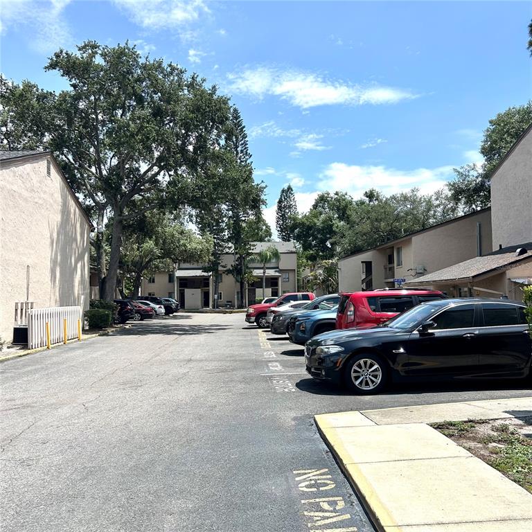 A parking lot sits between two multi-story apartment buildings under a bright blue sky — 7531 PITCH PINE CIRCLE UNIT 197, TAMPA, FL