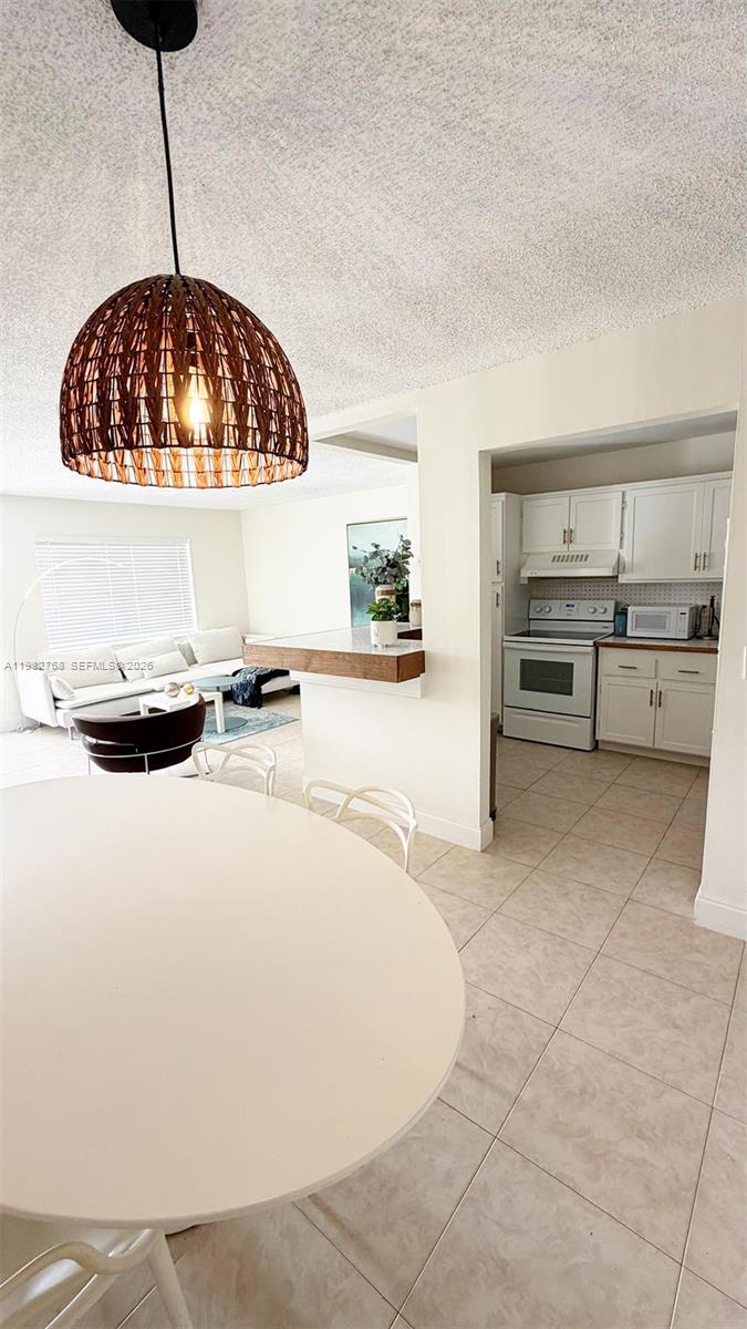 A dining area with a round table and pendant light overlooks a living room and kitchen — 2305 Lowson Blvd # B, Delray Beach FL 33445, DELRAY BEACH, FL
