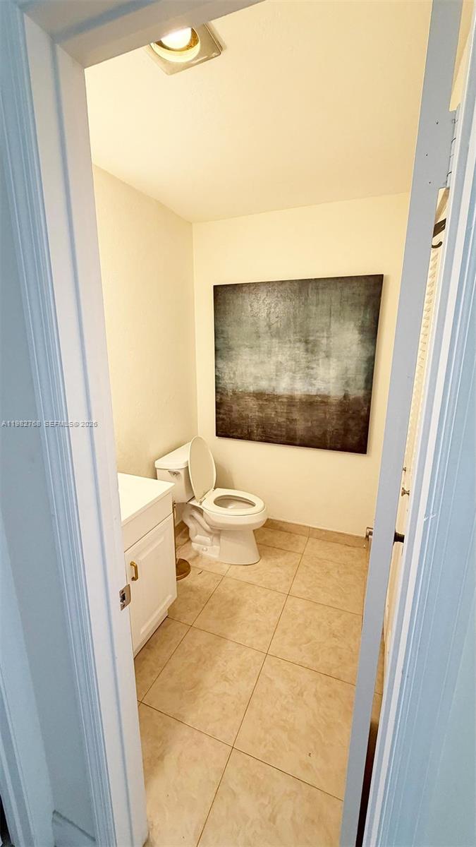 A small bathroom features a white vanity, a toilet, and a large abstract wall painting — 2305 Lowson Blvd # B, Delray Beach FL 33445, DELRAY BEACH, FL