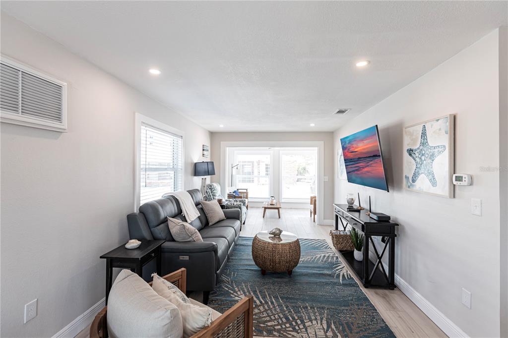 A living room features a gray sofa, a blue patterned rug, and a wall-mounted television — 6020 MIDNIGHT PASS ROAD UNIT 56, SARASOTA, FL