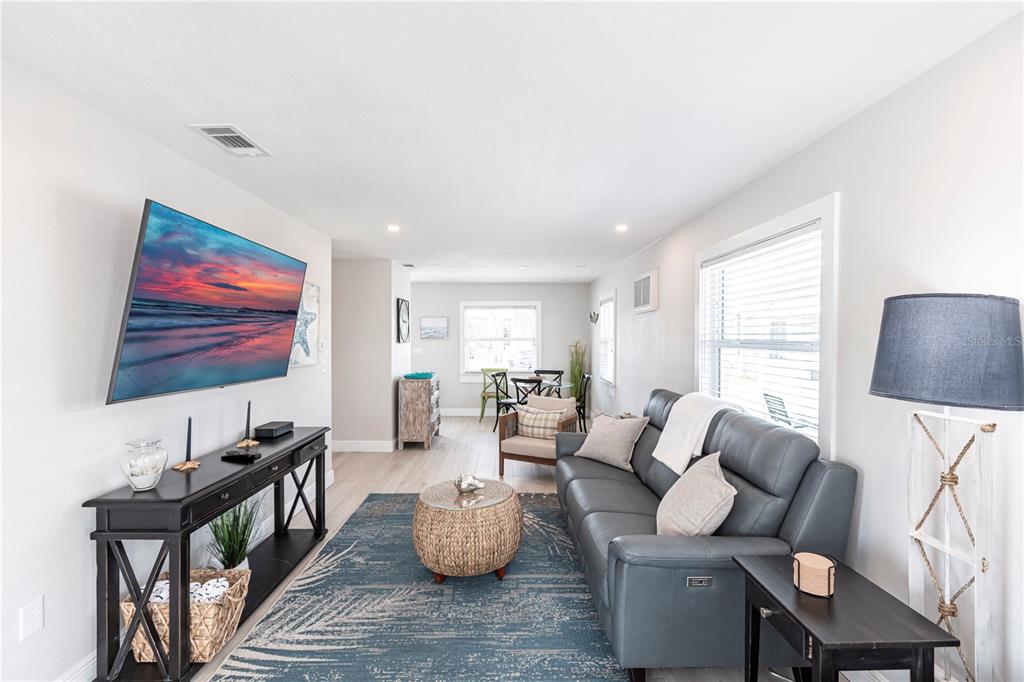 A living room features a grey sofa, a blue patterned rug, and a wall-mounted television — 6020 MIDNIGHT PASS ROAD UNIT 56, SARASOTA, FL