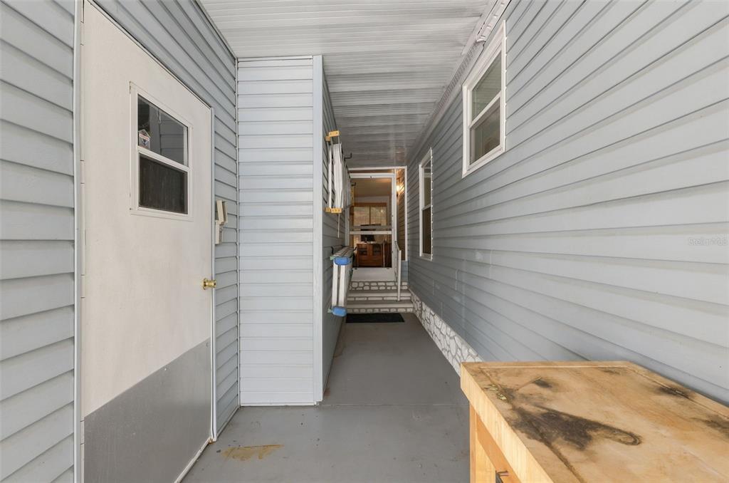 A covered outdoor walkway with light blue siding leads to a doorway and interior space — 530 TIVOLI PARK DRIVE, DAVENPORT, FL