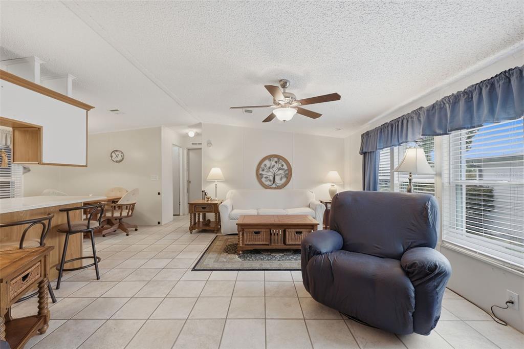 A living room with tile floors, a white sofa, a blue recliner, and a ceiling fan — 530 TIVOLI PARK DRIVE, DAVENPORT, FL