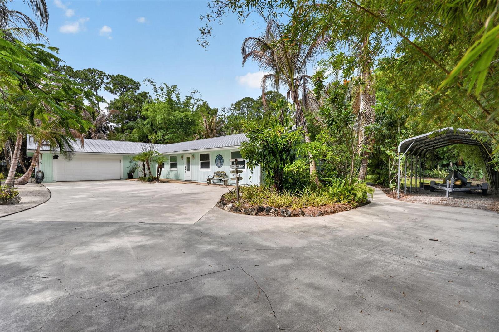 A light green single-story house with a metal roof, attached garage, and a carport — 17391 Alexander Run, Jupiter FL 33478, JUPITER, FL