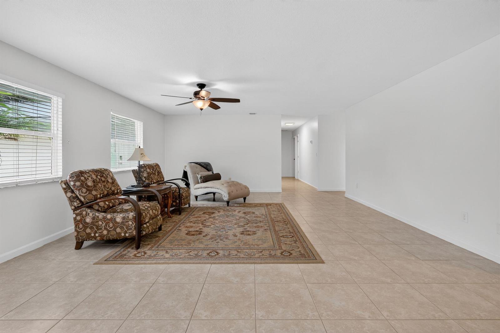 A living room with tile flooring, a ceiling fan, and a patterned area rug — 17391 Alexander Run, Jupiter FL 33478, JUPITER, FL