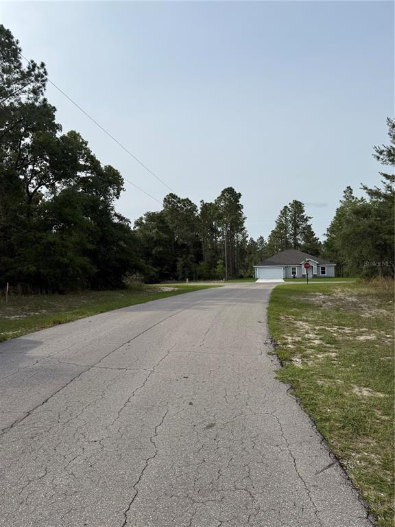 A paved road leads toward a single-story house surrounded by trees — TBD SW 128TH PLACE, OCALA, FL