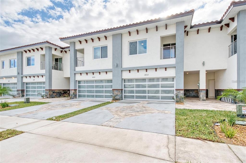 A row of modern two-story townhomes with white stucco facades, gray accents, and glass garage doors — 1815 BRENTWOOD COURT, DAVENPORT, FL