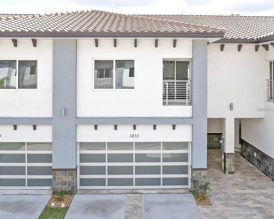 A two-story townhouse exterior features a white facade, gray trim, and a modern garage door — 1815 BRENTWOOD COURT, DAVENPORT, FL