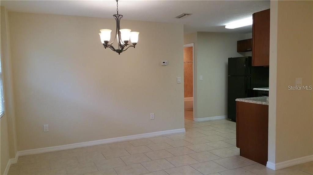 An empty room features light-colored tile flooring, a ceiling fan, and two windows — 1856 DEBBIE STREET Unit A, SARASOTA, FL