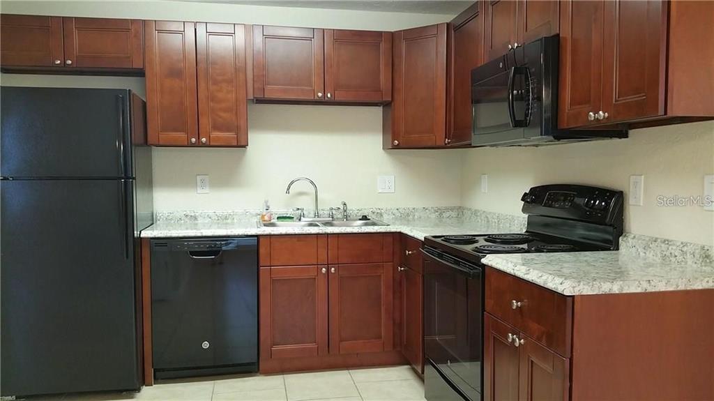 An empty room features beige tile flooring, white walls, and a ceiling fan with lights — 1856 DEBBIE STREET Unit A, SARASOTA, FL