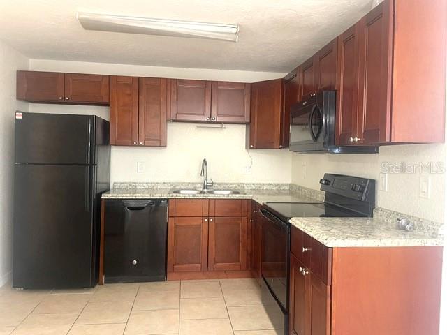 A kitchen features dark wood cabinets, black appliances, and light-colored tile flooring — 1856 DEBBIE STREET Unit A, SARASOTA, FL