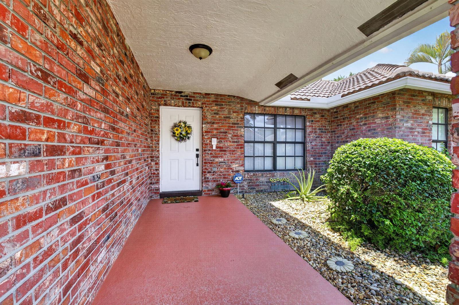 A brick house exterior features a covered porch, a white front door, and a landscaped yard — 19600 Sedgefield Terrace, Boca Raton FL 33498, BOCA RATON, FL