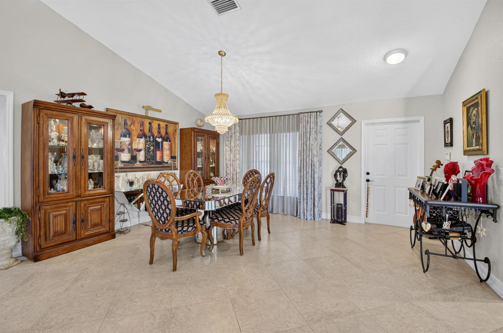 A dining room features a glass-topped table, wooden cabinets, a crystal chandelier, and tile flooring — 19600 Sedgefield Terrace, Boca Raton FL 33498, BOCA RATON, FL