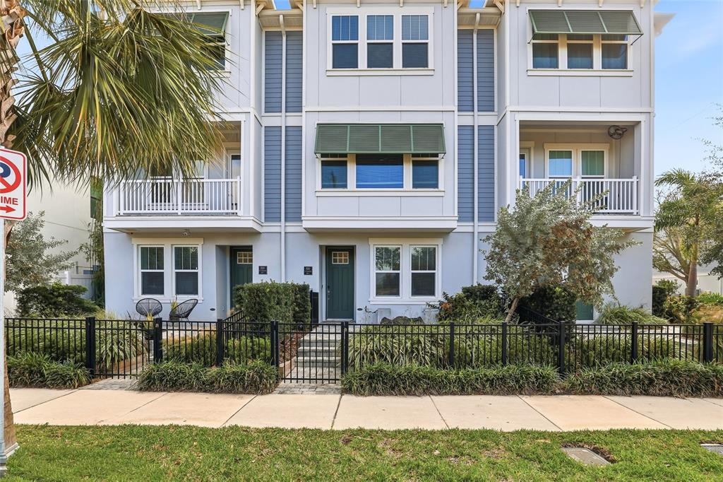 A three-story townhouse with light blue siding, green awnings, and a black metal fence — 2510 W CLEVELAND STREET UNIT 2, TAMPA, FL