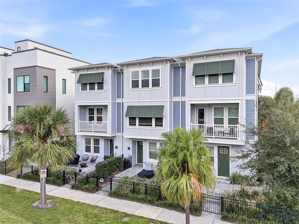 A three-story townhouse with light blue siding, green awnings, and palm trees in the front — 2510 W CLEVELAND STREET UNIT 2, TAMPA, FL