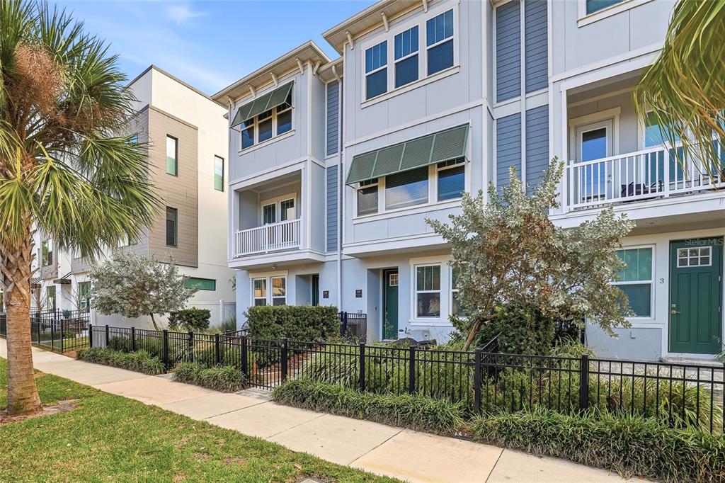 A three-story townhouse with light blue siding, green awnings, and a black metal front fence — 2510 W CLEVELAND STREET UNIT 2, TAMPA, FL