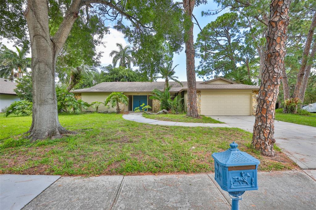 A single-story house with a beige facade, stone accents, and blue double doors — 2823 HERON PLACE, CLEARWATER, FL