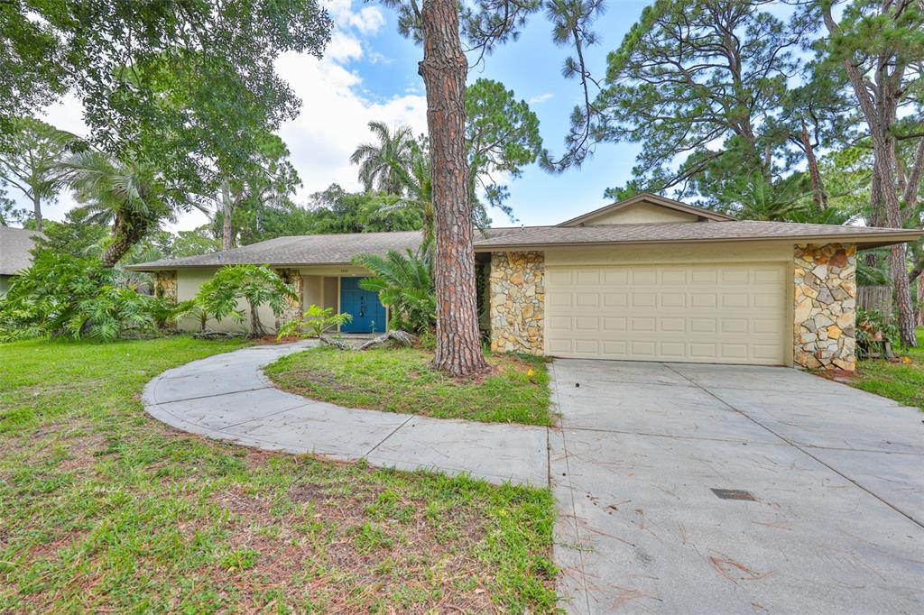 A single-story house with a stone facade, a two-car garage, and a curved concrete walkway — 2823 HERON PLACE, CLEARWATER, FL