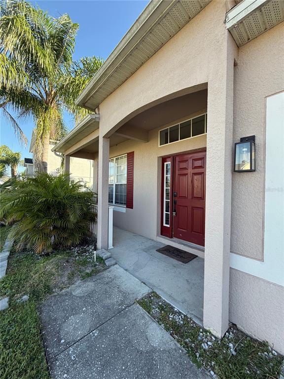 A covered concrete porch leads to a red front door with a side window — 368 CONCH KEY WAY, SANFORD, FL