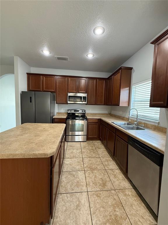 A kitchen features dark wood cabinets, stainless steel appliances, and a central island — 368 CONCH KEY WAY, SANFORD, FL