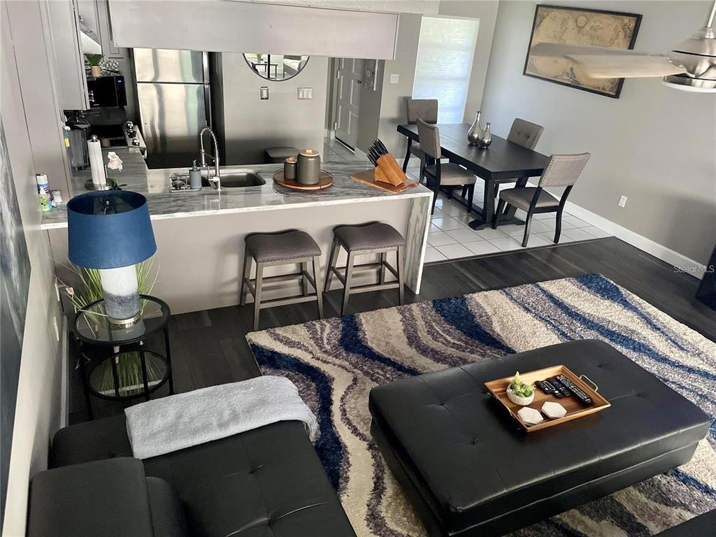 An open-concept living room and kitchen featuring a breakfast bar, dining area, and area rug — 2595 CYPRUS DRIVE UNIT 4-217, PALM HARBOR, FL